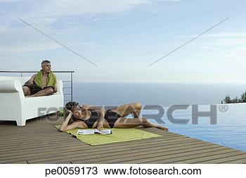Stock Photo - man and woman 
on deck by infinity 
pool. fotosearch 
- search stock 
photos, pictures, 
images, and photo 
clipart