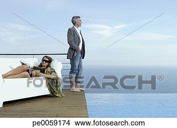 Stock Photo - man and woman 
on deck by infinity 
pool. fotosearch 
- search stock 
photos, pictures, 
images, and photo 
clipart