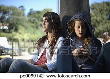 Stock Photo - two girls leaning 
against a tree 
with an mp3 player. 
fotosearch - search 
stock photos, 
pictures, images, 
and photo clipart