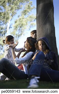 Stock Photo - woman sitting 
under tree with 
three girls. fotosearch 
- search stock 
photos, pictures, 
images, and photo 
clipart