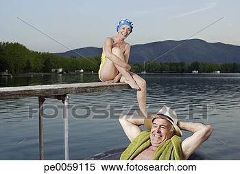 Stock Image - woman sitting 
on wooden plank 
over lake with 
man in inner tube. 
fotosearch - search 
stock photos, 
pictures, images, 
and photo clipart