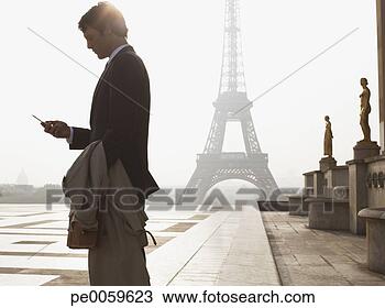 Stock Photo - businessman outdoors 
with cellular 
phone by eiffel 
tower. fotosearch 
- search stock 
photos, pictures, 
images, and photo 
clipart