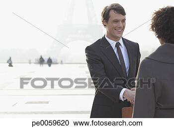 Stock Photography - two businesspeople 
outdoors shaking 
hands by eiffel 
tower. fotosearch 
- search stock 
photos, pictures, 
images, and photo 
clipart