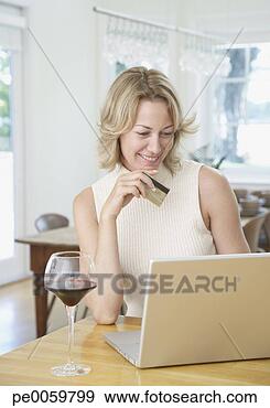 Stock Photograph - woman in kitchen 
with laptop and 
credit card. fotosearch 
- search stock 
photos, pictures, 
images, and photo 
clipart