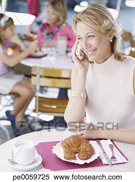 Stock Image - woman on outdoor 
patio with mobile 
phone and croissant. 
fotosearch - search 
stock photos, 
pictures, images, 
and photo clipart
