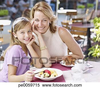 Stock Image - woman and young 
girl on outdoor 
patio eating meal. 
fotosearch - search 
stock photos, 
pictures, images, 
and photo clipart
