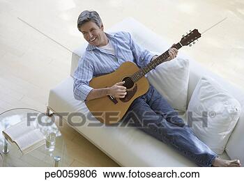 Stock Photo - man in living 
room playing acoustic 
guitar. fotosearch 
- search stock 
photos, pictures, 
images, and photo 
clipart