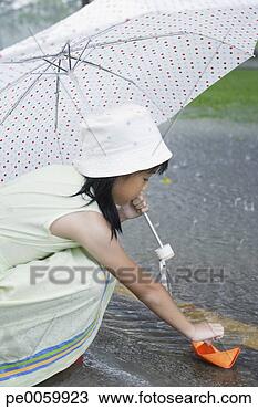 Banco de Imagem - jovem,  menina, 
 ao ar livre, 
 chuva,  tocando, 
 papel,  bote. 
fotosearch - busca 
de fotos, imagens 
e clipart