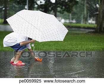 Banco de Imagem - jovem,  menina, 
 ao ar livre, 
 chuva,  tocando, 
 papel,  bote. 
fotosearch - busca 
de fotos, imagens 
e clipart