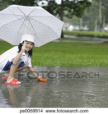 Stock Photo - young girl outdoors 
in rain playing 
with paper boat. 
fotosearch - search 
stock photos, 
pictures, images, 
and photo clipart
