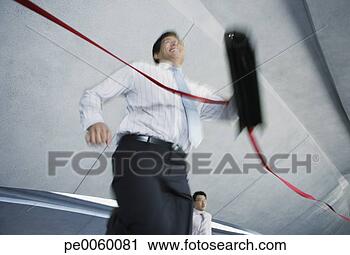 Stock Photography - businessman indoors 
crossing finish 
line with businessman 
behind him. fotosearch 
- search stock 
photos, pictures, 
images, and photo 
clipart