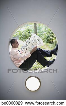 Stock Photograph - businessman sitting 
in round window 
reading newspaper. 
fotosearch - search 
stock photos, 
pictures, images, 
and photo clipart