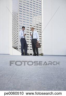Stock Photography - two businessman 
standing outdoors 
looking at their 
mobile phones. 
fotosearch - search 
stock photos, 
pictures, images, 
and photo clipart