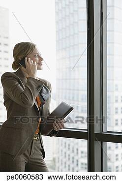 Stock Photo - businesswoman 
on her mobile 
phone in corridor 
by large windows. 
fotosearch - search 
stock photos, 
pictures, images, 
and photo clipart