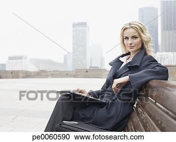 Arquivo de Fotografias - executiva,  sentando, 
 ao ar livre, 
 banco,  olhar, 
 câmera. fotosearch 
- busca de fotos, 
imagens e clipart