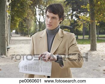 Arquivo de Fotografia - homem negócios, 
 ao ar livre, 
 parque,  segurando, 
 jornal. fotosearch 
- busca de fotos, 
imagens e clipart