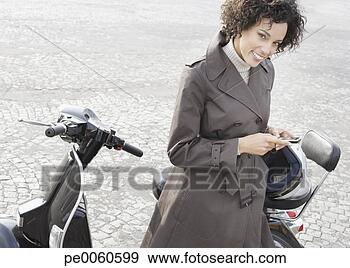 Arquivo Fotográficos - mulher,   ao ar 
livre,   inclinar-se, 
  scooter,   segurando. 
fotosearch - busca 
de fotos, imagens 
e clipart