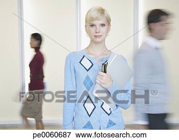 Picture - businesswoman 
in office holding 
folder with co-workers 
going by. fotosearch 
- search stock 
photos, pictures, 
images, and photo 
clipart