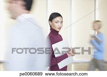 Stock Photograph - businesswoman 
in office holding 
folder with co-workers 
going by. fotosearch 
- search stock 
photos, pictures, 
images, and photo 
clipart