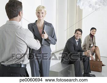Stock Photo - two businesspeople 
shaking hands 
in office lobby 
with two. fotosearch 
- search stock 
photos, pictures, 
images, and photo 
clipart