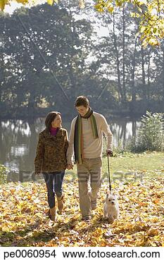Stock Photo - couple outdoors 
walking a dog 
by a lake. fotosearch 
- search stock 
photos, pictures, 
images, and photo 
clipart