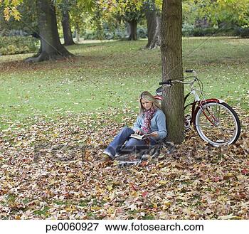Foto - mulher,  ao ar 
livre,  livro, 
 bicicleta,  inclinar-se, 
 árvore. fotosearch 
- busca de fotos, 
imagens e clipart