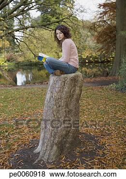 Banco de Imagem - mulher,  sentando, 
 livro,  ao ar 
livre,  lago, 
 toco. fotosearch 
- busca de fotos, 
imagens e clipart