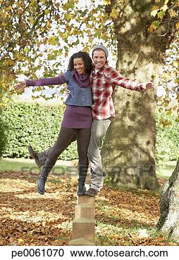Stock Photography - couple outdoors 
balancing on a 
wooden fence. 
fotosearch - search 
stock photos, 
pictures, images, 
and photo clipart