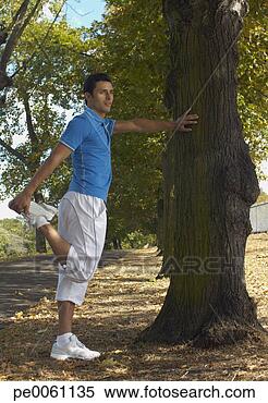 Stock Image - man leaning on 
a tree stretching 
outdoors in a 
park. fotosearch 
- search stock 
photos, pictures, 
images, and photo 
clipart