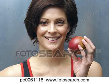 Stock Photo - woman standing 
in locker room 
holding apple. 
fotosearch - search 
stock photos, 
pictures, images, 
and photo clipart