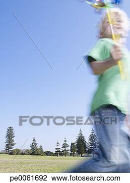 Banco de Imagem - jovem,  menino, 
 ao ar livre, 
 executando,  
moinho de vento. 
fotosearch - busca 
de fotos, imagens 
e clipart