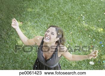 Stock Photo - woman outdoors 
standing on grass 
with champagne 
and confetti smiling. 
fotosearch - search 
stock photos, 
pictures, images, 
and photo clipart