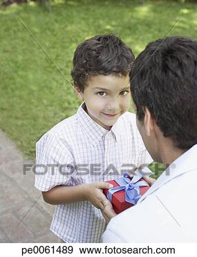 Stock Photograph - young boy outdoors 
smiling and giving 
man gift. fotosearch 
- search stock 
photos, pictures, 
images, and photo 
clipart