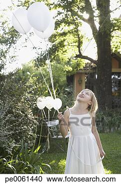 Stock Photography - young girl standing 
outdoors holding 
balloons and smiling. 
fotosearch - search 
stock photos, 
pictures, images, 
and photo clipart