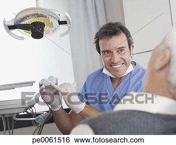 Stock Photo - dentist showing 
patient a mold 
of teeth and smiling. 
fotosearch - search 
stock photos, 
pictures, images, 
and photo clipart