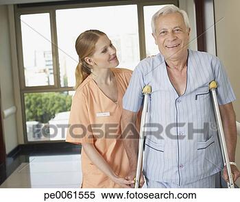 Stock Image - hospital worker 
helping senior 
man in hospital 
corridor using. 
fotosearch - search 
stock photos, 
pictures, images, 
and photo clipart