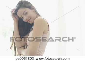 Stock Photo - woman standing 
indoors putting 
hands up to her 
head and smiling. 
fotosearch - search 
stock photos, 
pictures, images, 
and photo clipart