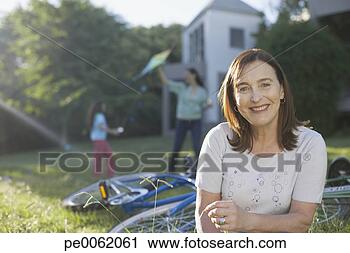 Arquivo de Fotografia - sênior,  mulher, 
 ficar,  ao ar 
livre,  bicycles, 
 sorrindo. fotosearch 
- busca de fotos, 
imagens e clipart