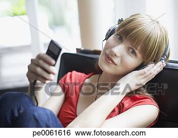 Banco de Imagem - mulher,  sentando, 
 vivendo,  sala, 
 escutar,  mp3, 
 jogador. fotosearch 
- busca de fotos, 
imagens e clipart