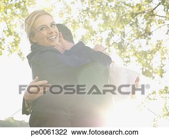 Banco de Imagem - par,  abraçar, 
 ao ar livre, 
 sorrindo. fotosearch 
- busca de fotos, 
imagens e clipart
