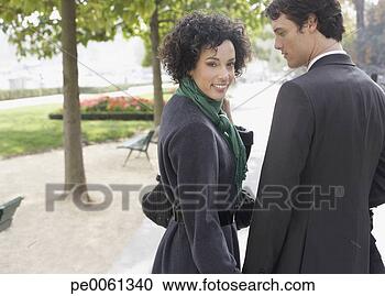 Arquivo de Fotografias - par,  ficar,  
ao ar livre,  
segurando,  mãos, 
 sorrindo. fotosearch 
- busca de fotos, 
imagens e clipart