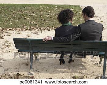 Arquivo de Fotografia - par,  sentando, 
 ao ar livre, 
 banco. fotosearch 
- busca de fotos, 
imagens e clipart