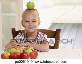 Arquivo Fotográficos - jovem,  menina, 
 cozinha,  equilibrar, 
 maçã,  cabeça, 
 sorrindo. fotosearch 
- busca de fotos, 
imagens e clipart