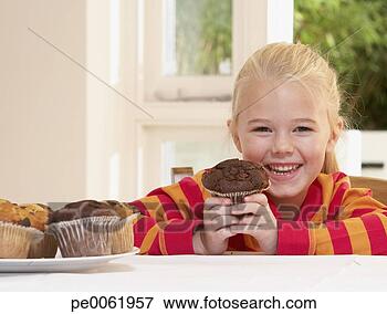 Foto - jovem,  menina, 
 cozinha,  segurando, 
 cupcake,  sorrindo. 
fotosearch - busca 
de fotos, imagens 
e clipart