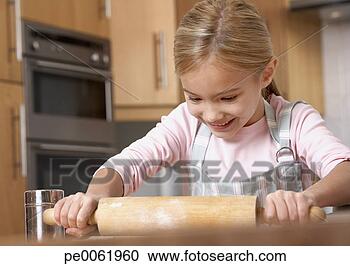 Arquivo de Fotografias - jovem,  menina, 
 cozinha,  usando, 
 rolando,  alfinete, 
 sorrindo. fotosearch 
- busca de fotos, 
imagens e clipart