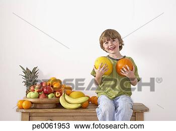 Stock Photo - young boy sitting 
on kitchen island 
with assorted 
fruit holding. 
fotosearch - search 
stock photos, 
pictures, images, 
and photo clipart