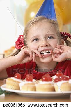 Stock Image - young girl at 
birthday party 
playing with party 
hat and smiling. 
fotosearch - search 
stock photos, 
pictures, images, 
and photo clipart