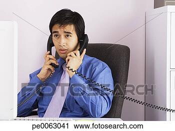 Arquivo de Fotografia - homem negócios, 
 falando,  dois, 
 telefones,  um, 
 tempo. fotosearch 
- busca de fotos, 
imagens e clipart