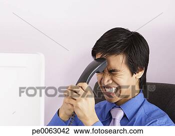 Banco de Imagem - homem negócios, 
 grimacing,  enquanto, 
 segurando,  telefone, 
 handset. fotosearch 
- busca de fotos, 
imagens e clipart