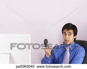 Arquivo de Fotografias - homem negócios, 
 segurando,  telefone, 
 handset. fotosearch 
- busca de fotos, 
imagens e clipart